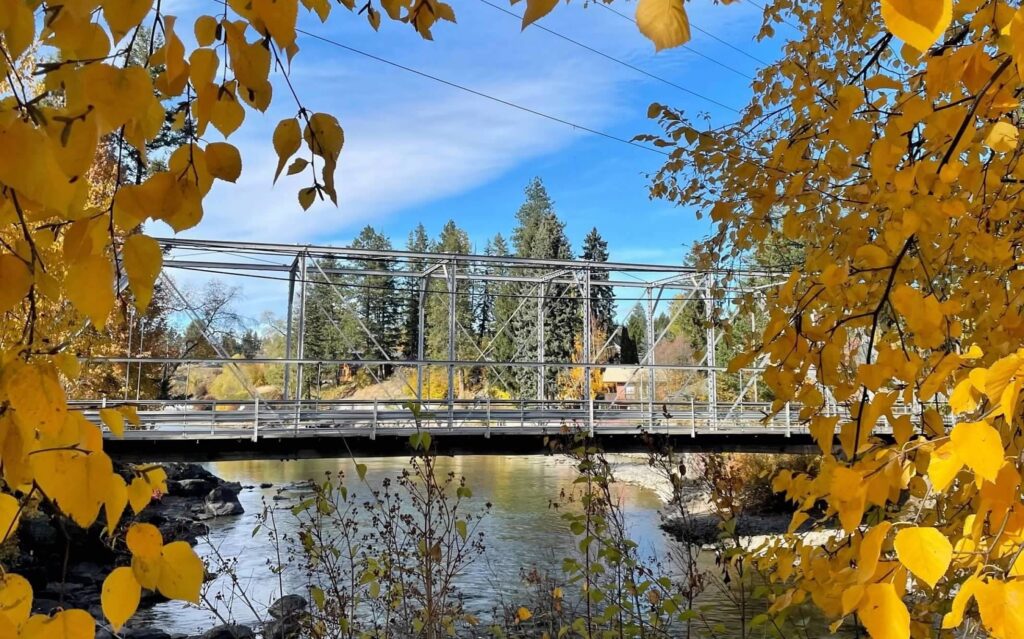 Image of single lane bridge in Bigfork with fall leaves framing it